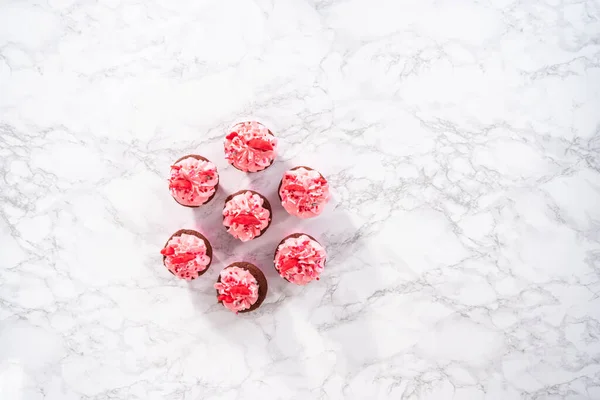 平置きだ 赤いベルベットのカップケーキピンクイタリアのバタークリームの霜降りとハートとキス形の赤いチョコレートで飾られています — ストック写真