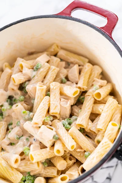 Alfredo soslu tavuk pişirmek için mayalı bir fırının içindekileri karıştırıyorum..