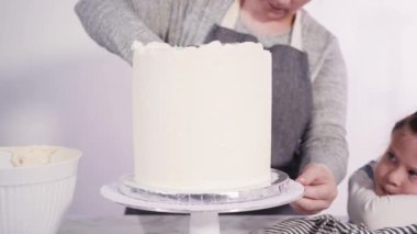 Adım adım. Pembe tereyağlı krema kaplı yuvarlak funfetti kek katmanları.