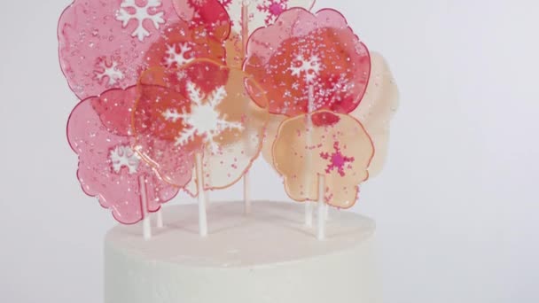 大きなロリポップと雪の結晶を背の高い白い丸いケーキに入れて最終的な装飾として — ストック動画