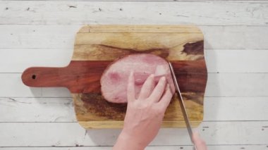 Ağaç kesme tahtasıyla organik ballı jambon kesmek.