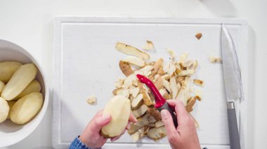 Düz yatıyordu. Adım adım. Beyaz ahşap bir tahtanın üzerinde sebze soyuculu büyük sarı patatesleri soyuyordu..