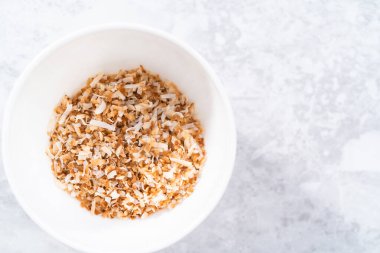 Beyaz bir seramik kasede kızarmış hindistan cevizi taneleri..