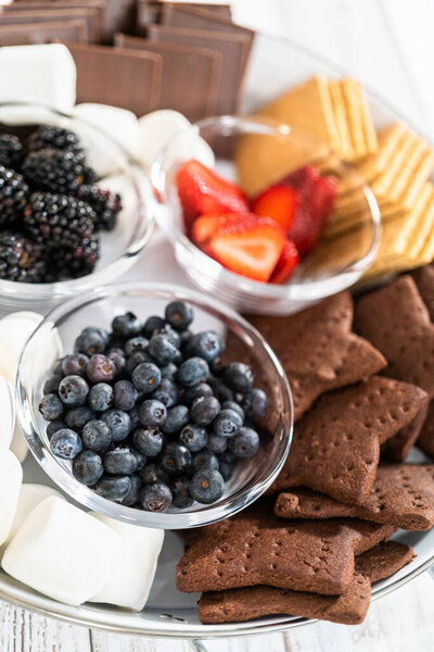 Arranging fruit s'mores charcuterie board on a white tray.