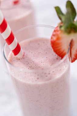 Taze taze çilek ve kağıt kamışla süslenmiş sağlıklı bir kahvaltı muzlu smoothie..