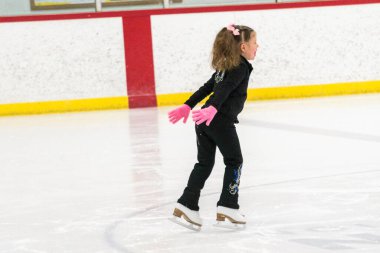 Küçük kız buz pistinde artistik patinaj yapıyor..