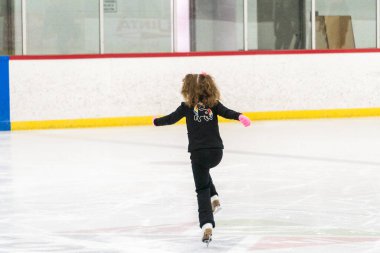 Küçük kız buz pistinde artistik patinaj yapıyor..