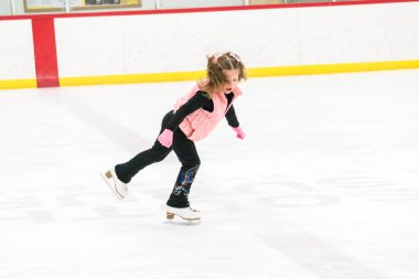 Küçük kız buz pistinde artistik patinaj yapıyor..