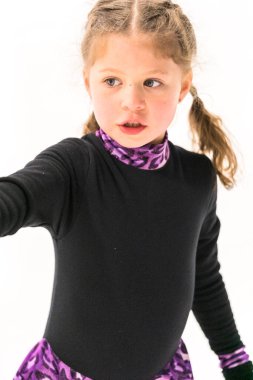 Küçük kız buz pateni pistinde artistik patinaj yapıyor..