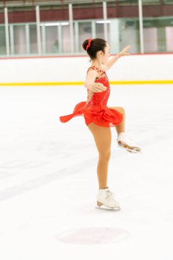 Genç kız buz pateni pistinde artistik patinaj yapıyor..