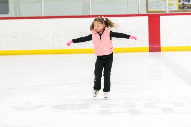 Küçük kız buz pistinde artistik patinaj yapıyor..