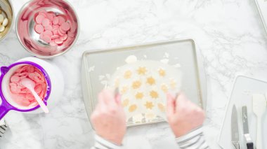 Düz yatıyordu. Adım adım. Çikolatalı kar tanelerini plastik çikolata kalıbından kurabiye tepsisine atmak..