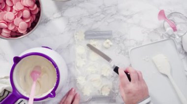 Mermer tezgahın üzerindeki beyaz fondanla kar tanelerini keserek..