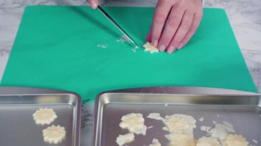 Mermer tezgahın üzerindeki beyaz fondanla kar tanelerini keserek..