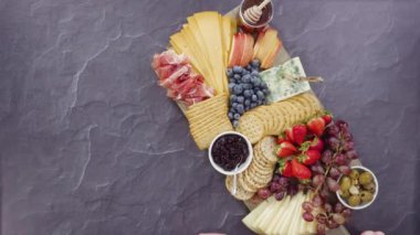 Büyük bir peynir tahtası için tahtanın üzerinde gurme peynir, kraker ve meyve düzenlemek..