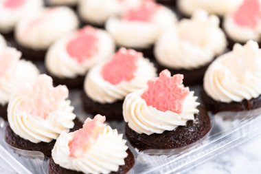 İtalyan tereyağı kremalı çikolatalı mini kekler. Parlak çikolatalı kar taneleriyle süslenmiş..