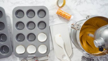 Düz yatıyordu. Balkabağı aromalı kek hamuru. Hamur hamuru kepçesiyle kapkek tepsisine dolgu malzemesi..