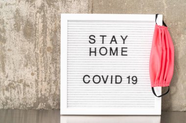 Evde Kal ve COVID-19 tabelasında ev yapımı yüz maskesi var..