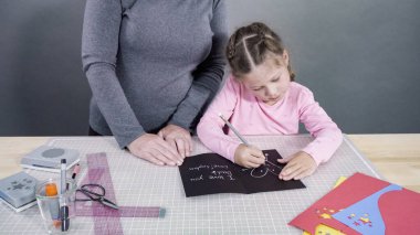 İnşaat kağıdından el yapımı Babalar Günü kartı yapan küçük bir kız..