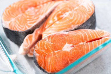 Izgara için cam bir tabakta marine edilmiş somon bifteği..