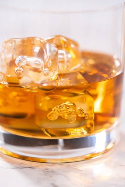 Buzlu viski, viski bardağında, beyaz mermer yüzeyde..