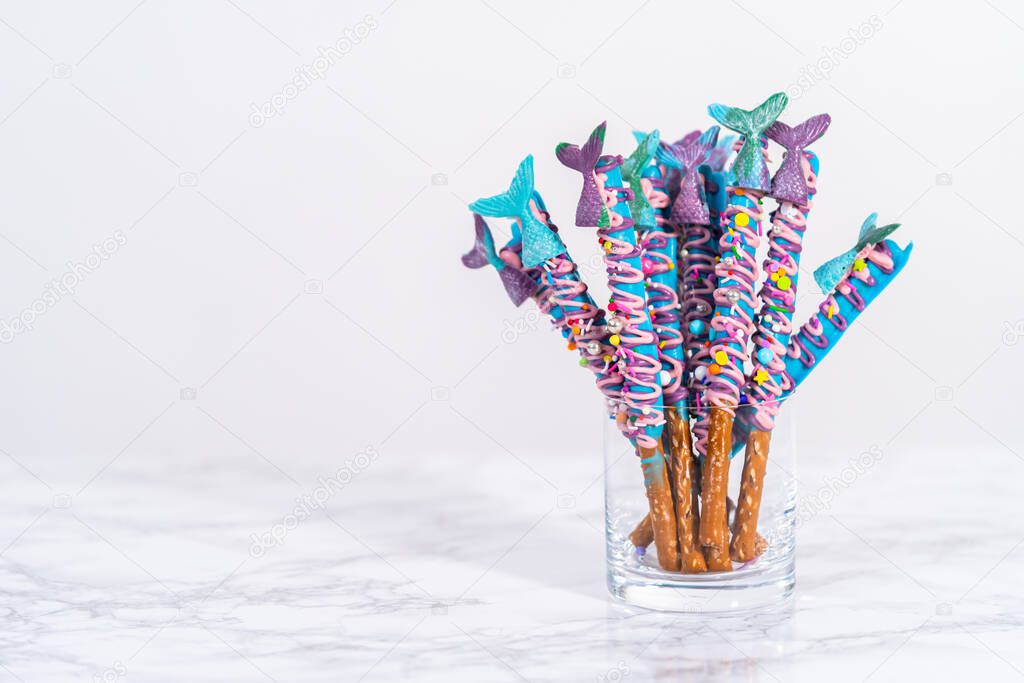 Mermaid chocolate pretzel rods drizzled with pink and purple chocolate and covered with sprinkles.