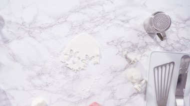 Düz yatıyordu. Adım adım. Mermer tezgahın üzerindeki beyaz fondanla kar tanelerini keserek..