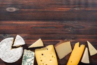 Düz yatıyordu. Koyu ahşap arka planda büyük gurme peynir dilimleri var..