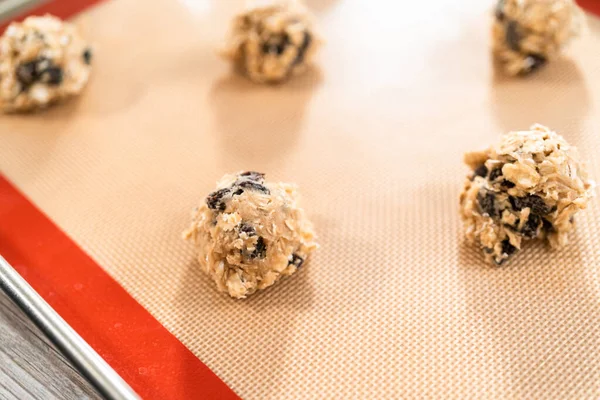 Scoops of cookie dough on a baking cheets to bake chewy oatmeal raisin cookies.