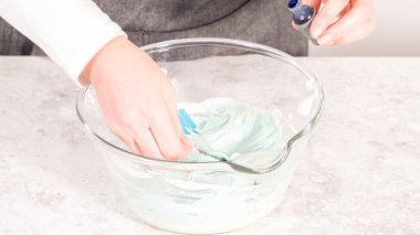 Adım adım. Tereyağlı kremaya mavi gıda boyası karıştırıyorum..