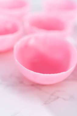 Sıcak çikolata bombaları hazırlamak için silikon çikolata kalıplarından erimiş pembe çikolata kabuklarını çıkarıyorum..