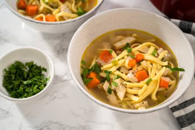 Beyaz seramik çorba kaselerinde kluski şehriyeli tavuk çorbası servis ediyorum..