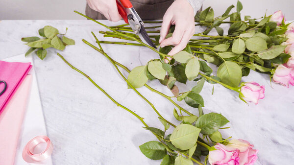 Step by step. Florist arranging a bouquet from pink roses.