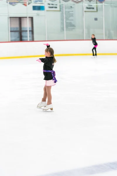 Kleines Mädchen Übt Eiskunstlauf Auf Einer Überdachten Eisbahn — Stockfoto