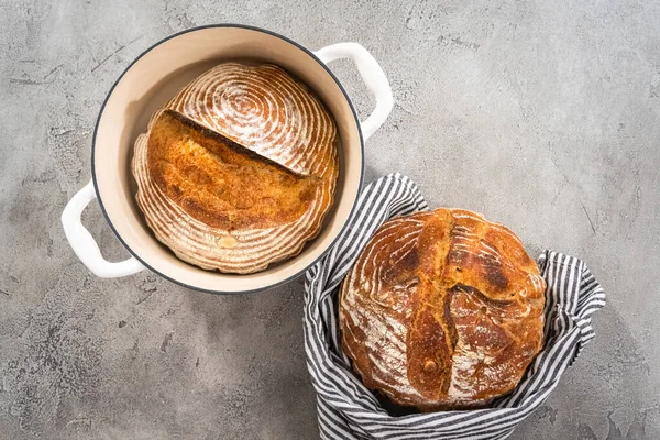 Flat lay. Freshly baked loaf of a wheat sourdough bread with marks from bread proofing basket in enameled cast iron dutch oven.