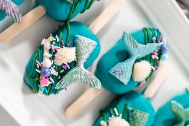 Çikolatalı deniz kızı kekleri, çikolatalı deniz kızı kuyruğu, deniz kabuğu ve serpiştirilmiş..