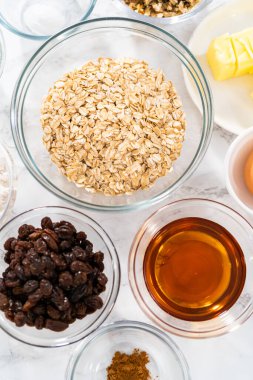 Yumuşak yulaf ezmesi üzümlü cevizli kurabiye pişirmek için cam karışımında ölçülmüş malzemeler..