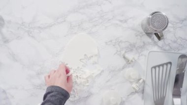 Mermer tezgahın üzerindeki beyaz fondanla kar tanelerini keserek..