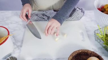 Düz yatıyordu. Beyaz bir kesme tahtasıyla organik sarımsak kesmek.