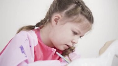 Küçük kız COVID-19 salgını sırasında evde uzaktan öğrenim için sanat projesi üzerinde çalışıyor..