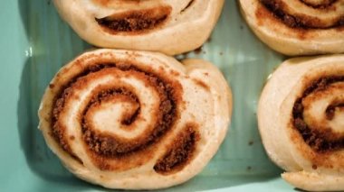 Fırınlanmamış tarçınlı çörekler mavi bir tavada.