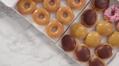 Beyaz bir karton kutuda mağazadan alınmış donutların çeşitliliği.