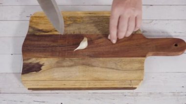 Düz yatıyordu. Beyaz bir kesme tahtasıyla organik sarımsak kesmek.