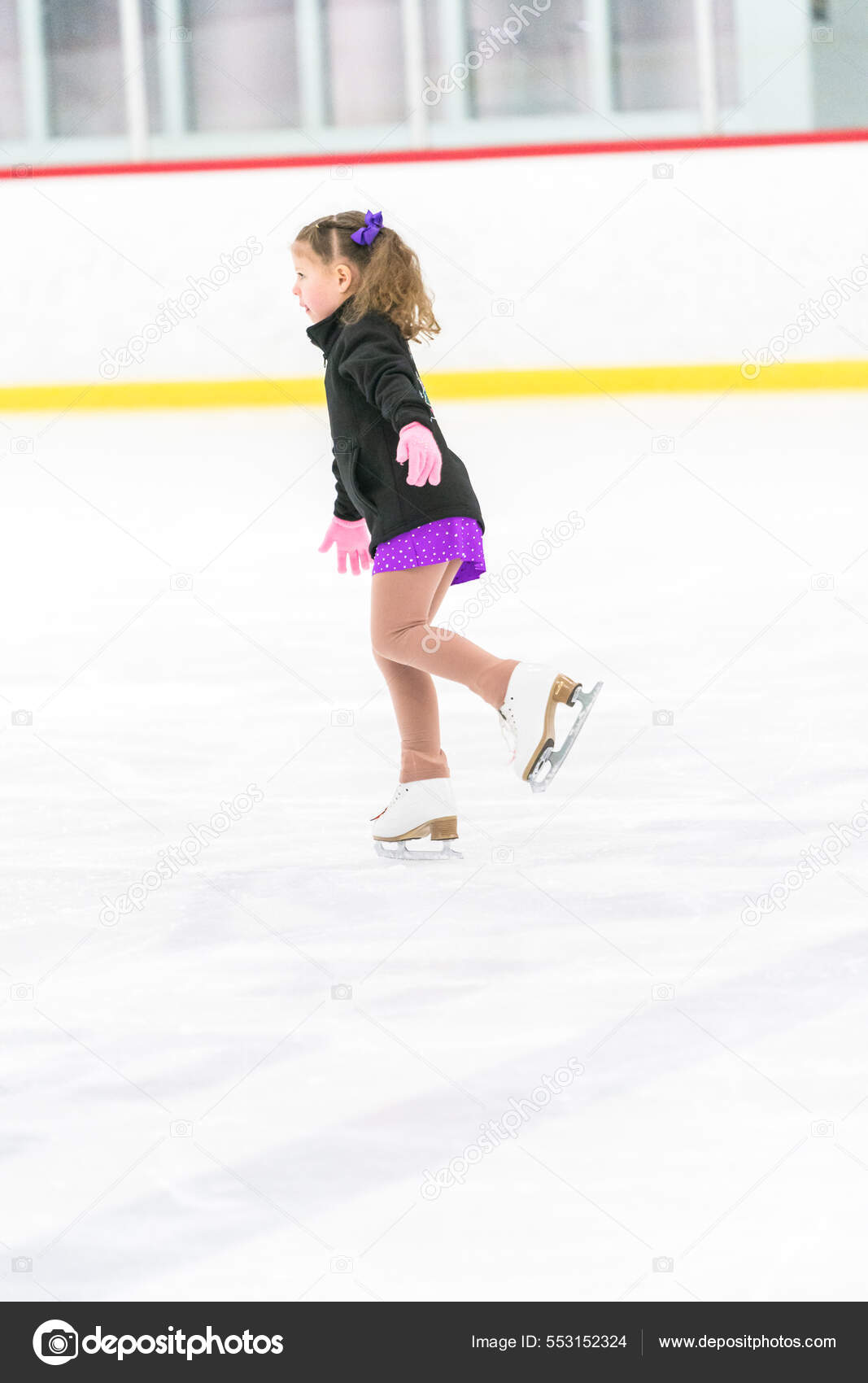 Niña practicando patinaje artístico en una pista de patinaje sobre hielo  cubierta