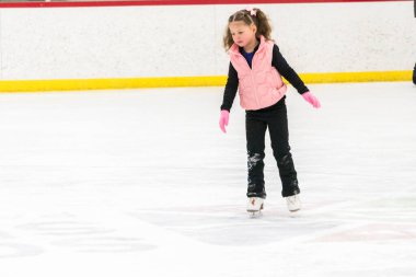 Küçük kız buz pistinde artistik patinaj yapıyor..