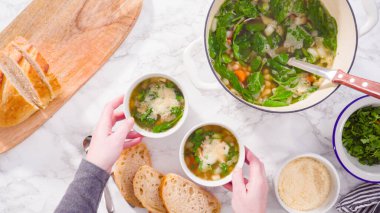 Beyaz kaselerde vejetaryen beyaz fasulye çorbası servis ediyorlar..