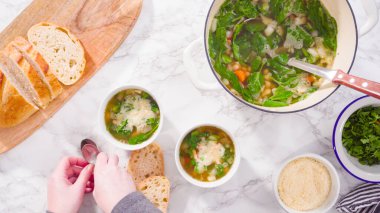 Beyaz kaselerde vejetaryen beyaz fasulye çorbası servis ediyorlar..