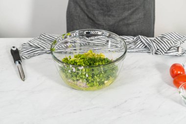 Klasik guacamole sosu yapmak için beyaz kesim tahtasındaki malzemeleri kesiyorum..