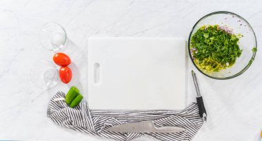 Düz yatıyordu. Klasik guacamole sosu yapmak için beyaz kesim tahtasındaki malzemeleri kesiyorum..