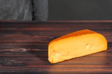 Koyu ahşap arka planda büyük bir kaşık füme Gouda peyniri..